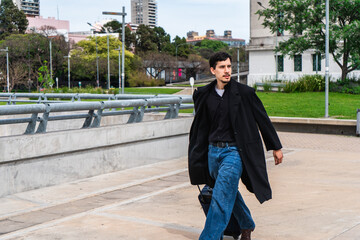 Young man walking through urban park with luggage