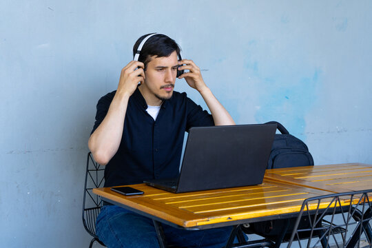 Man working remotely at cafe table wearing headphones - Powered by Adobe