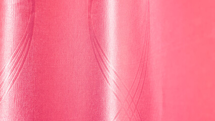 Close-up of a vibrant pink or magenta satin fabric background with vertical folds and an elegant, flowing, slightly wrinkled texture.