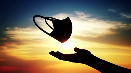 Silhouette Hand Reaching for a Floating Mask. Hope and Release in a Vibrant Sunset Sky. Uplifting Theme of Freedom and Liberation.