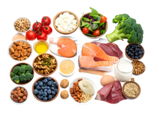 A variety of fresh vegetables, fruits, nuts, dairy, and protein sources arranged on a surface for healthy eating options