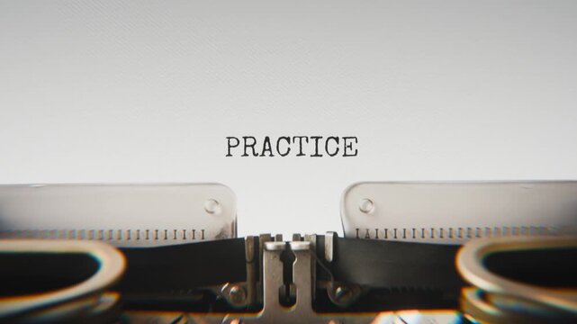 Old mechanical typewriter typing Practice in a close-up view, with metal letters striking the white paper.