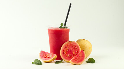 Refreshing guava juice in a plastic cup and straw, accompanied by whole and sliced ​​guava on a white background

