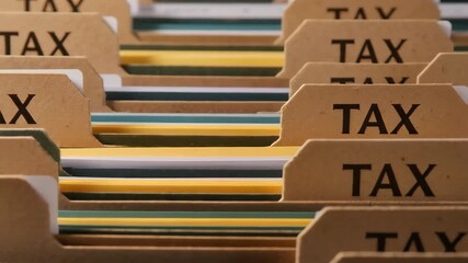 Close-up of organized tax files in a filing cabinet with labeled folders in a range of colors