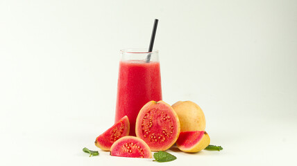 A large glass of fresh guava juice surrounded by guava slices on a white background
