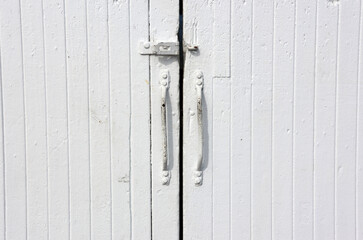 Close-up of white wooden doors with long handles