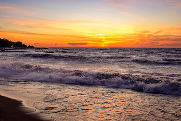 New beginnings: sunrise on a beach with waves breaking on sand room for text suitable as back drop or banner shot on Kew Beach in Toronto