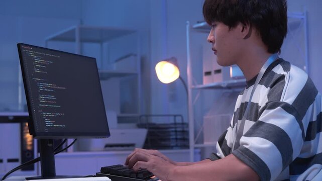 One young male Asian IT freelancer programmer and tech engineer working with computer keyboard, typing software codes for application development and website network system information data in room.