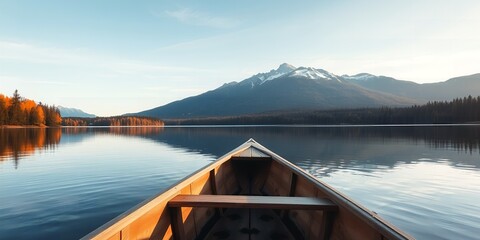 Wooden canoe on a calm lake reflecting snow capped mountains and autumn trees water