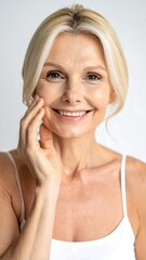Smiling blond woman with hand on cheek, wearing a white top