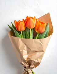 Three vibrant orange tulips bundled in brown paper