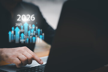 Businessman drawing digital growth arrows and bar graph with 2026 target. Futuristic concept for business goals, technology strategy, data-driven planning, success and innovation.