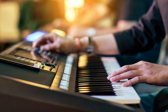 Hands of male musician press digital electronic keyboard synthesizers on concert stage. Pianist man hands play the keys of electronic piano. Piano music pianist hand playing. Selective focus on hand.