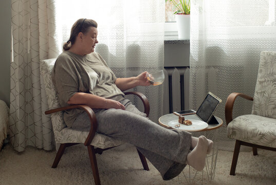 An elderly woman uses a tablet and looks at the screen at home in the morning