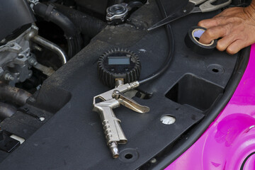Focused mechanic performs car diagnostic and repair with pressure gauge tool. man hand holds tape for maintenance on vehicle engine in an auto service garage