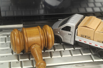 Truck model with many carton boxes and judge gavel on laptop computer close up. Legal regulation of...