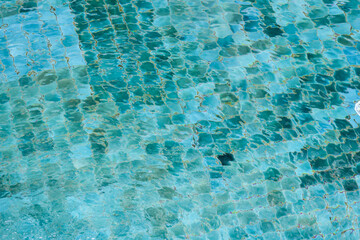 Refreshing background of blue turquoise water in swimming pool. shimmering surface ripples over serene mosaic tile texture, creating peaceful and calm feeling