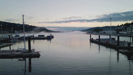 A serene harbor bathed in soft light, offering a tranquil scene of boats at dock, a misty expanse, and the gentle hues of dawn.