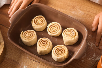 Baking dish with raw cinnamon rolls on table in kitchen