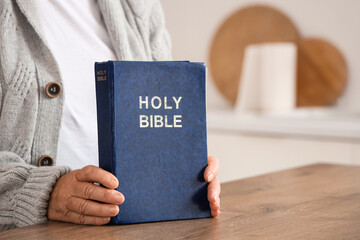 Senior woman with Bible at home, closeup