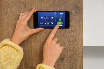 Young woman using smart home security system control panel in kitchen, closeup