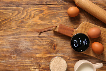 Modern kitchen timer, ingredients and different utensils on wooden background