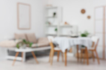 Blurred view of light dining room with table, couch and shelf units