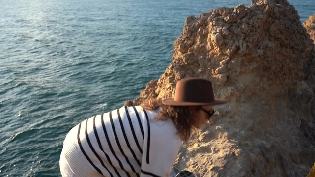 Adventurous Traveler Posing on Cliffside During Golden Hour Ocean View