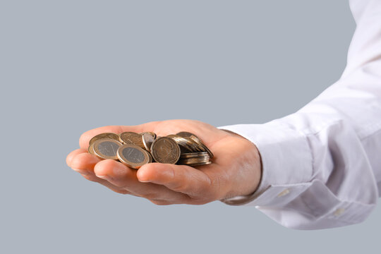 Hand of businessman with coins on grey background