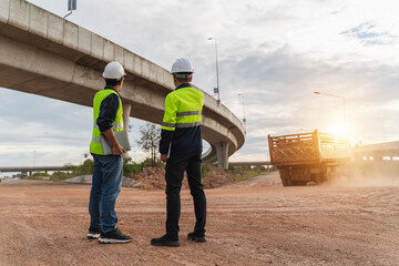 Construction Workers Observing Road Work with Heavy Truck Under a Dramatic Sky in Evening Light
