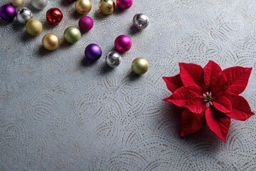 Vibrant red poinsettia flower with a scattering of colorful christmas ornaments on a textured gray background