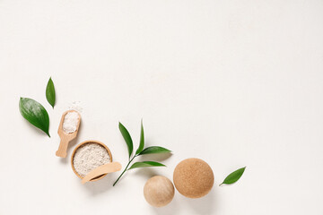 Spa composition with cosmetic clay, sea salt, massage balls and plant leaves on light background