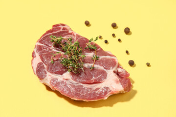 Fresh raw steak with thyme and peppercorns on yellow background, closeup