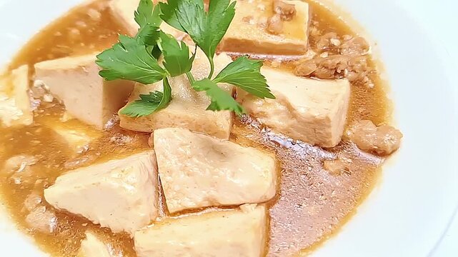 Close-up of Mun Tahu, a Chinese-Indonesian dish with silken tofu and minced beef in a savory, slightly spicy sauce.