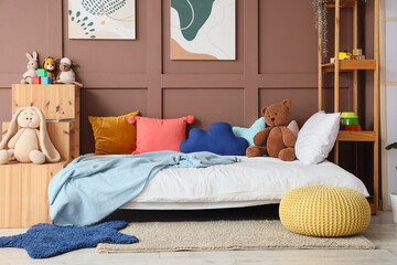 Comfortable bed and shelving units near brown wall in interior of children's room