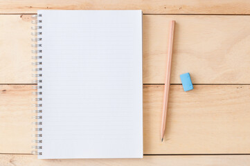 Blank notebook with pencil & eraser on wooden background