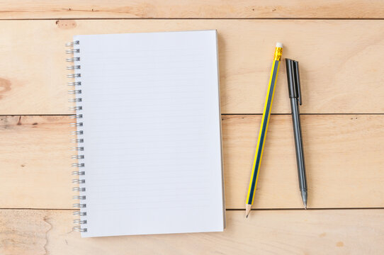 Blank notebook with pencil & pen on wooden background