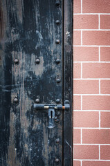 Close up at black metal door on brick wall