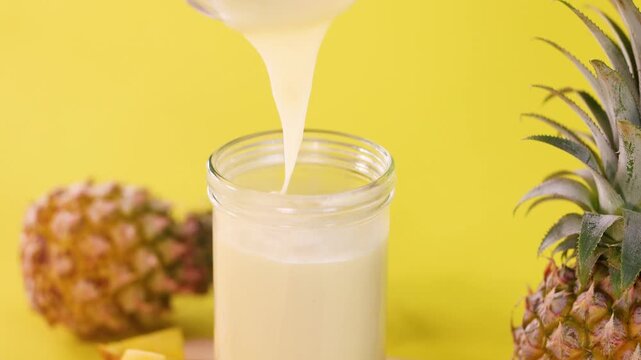 Pouring Pineapple Smoothie Into Glass With Fresh Fruit Background