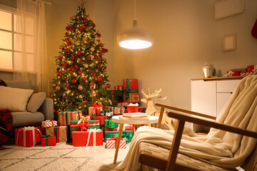 Interior of festive room with sofa, armchair, coffee table, Christmas tree, many gift boxes and decorations on commode in evening