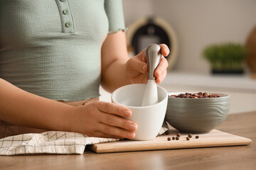 Woman with mortar, red beans and peppercorns at table in kitchen, closeup