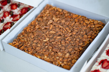 The square slice of toffee cake with cashew nut and caramel syrup in white box.