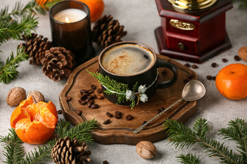Wooden board with mug of coffee, tangerines, forest bumps and fir branches on grey background