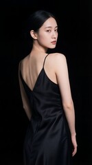 Naklejka premium 暗闇の中で振り返る黒いキャミソールドレスの女性