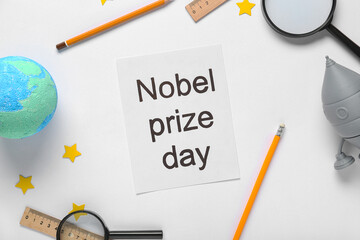 Fototapeta premium Paper with text NOBEL PRIZE DAY, earth model, rocket and stationery on white background