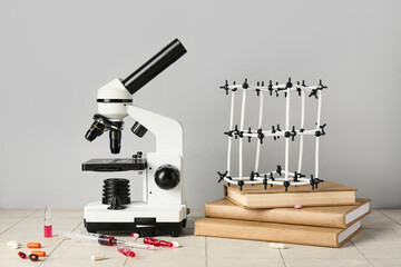 Molecular model with microscope, books, ampules and pills on tile against grey background. Nobel Prize Day