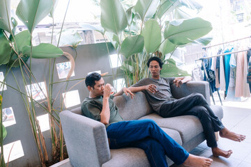 Two men relax on a comfortable sofa enjoying drinks