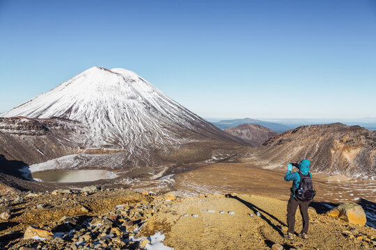 Woman taking a photo of volcano, Tongariro crossing, New Zealand