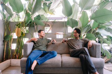 Friends enjoying relaxed conversation on sofa amidst lush green plants