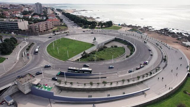 Aerial orbit around Pra&ccedil;a Gon&ccedil;alves Zarco, the iconic roundabout by the seaside promenade near Castelo do Queijo, Matosinhos, Porto, Portugal, with Avenida de Montevideu and oceanfront in frame.